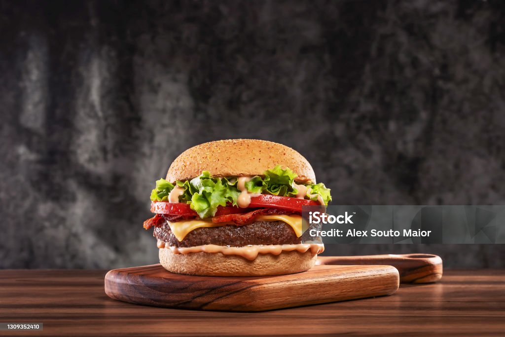 Cheeseburger with tomato and lettuce on wooden board Cheeseburger with tomato and lettuce on wooden plank Burger Stock Photo