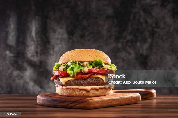 Cheeseburger With Tomato And Lettuce On Wooden Board Stock Photo - Download Image Now