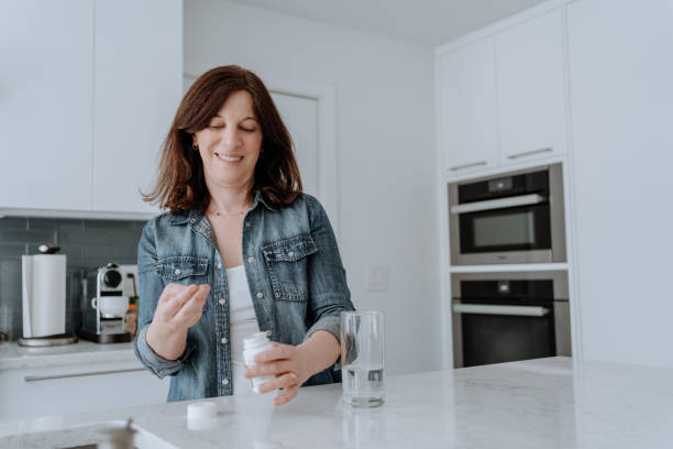istock Woman taking vitamins in the kitchen 1309357968