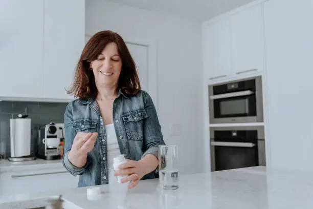 Woman taking vitamins in the kitchen