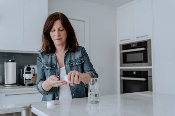 istock Woman taking vitamins in the kitchen 1309357992
