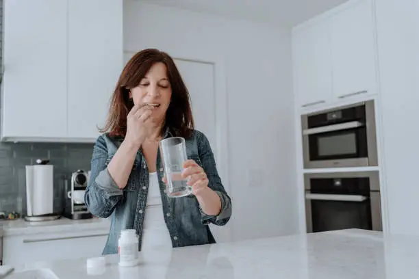 Woman taking vitamins in the kitchen