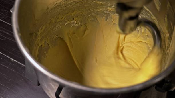 istock Mixing dough for bread baking with professional kneader spiral machine at the manufacturing. The dough is kneaded for burgers. 1309360572