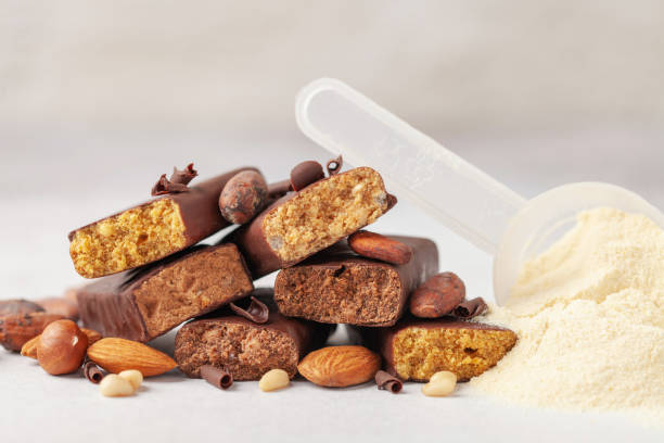 Whey protein powder in measuring scoop and different energy protein bar on grey background.