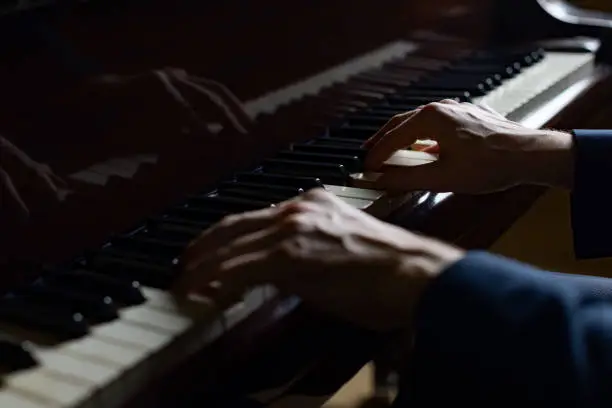 Hands of pianist man on the grand piano keyboard (selective focus)