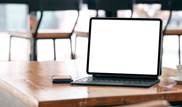 istock Mockup blank screen tablet with magic keyboard on wooden table in cafe. 1309367826