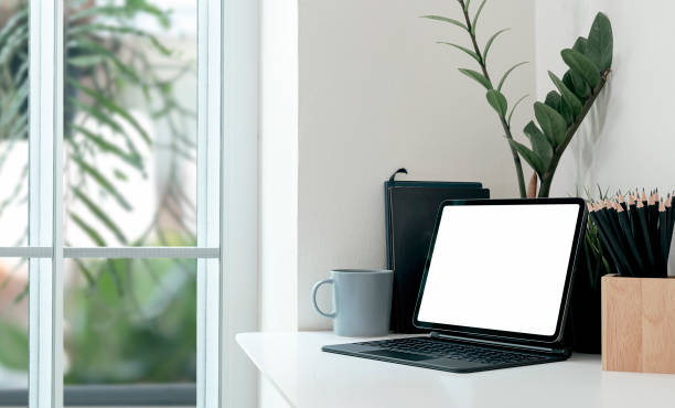 istock Mockup creative workspace with blank screen tablet on white top table in modern room. 1309367930
