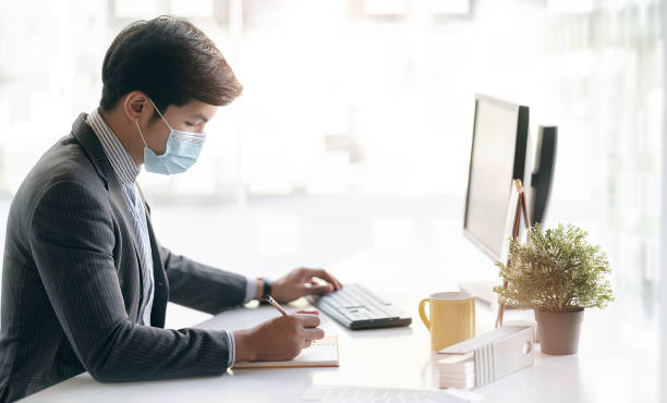 istock oung asian businessman with protective mask working on document. 1309367936