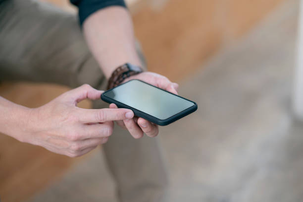 istock Closeup shot of man hands holding blank screen smartphone while sitting outdoors, shallow depth of field. 1309368726