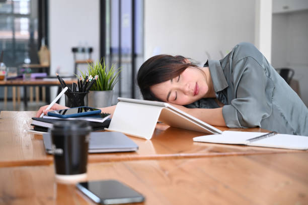istock Tired young woman office worker having a nap at her office desk. 1309370857