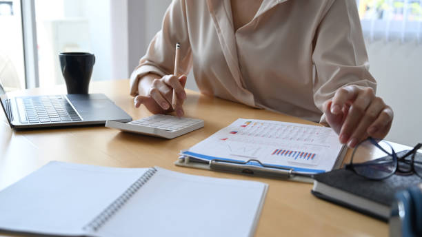 istock Female accountant using calculator and analysis financial data at office desk. 1309371086
