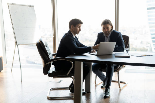 istock Smiling business partners work on laptop in office 1309380747