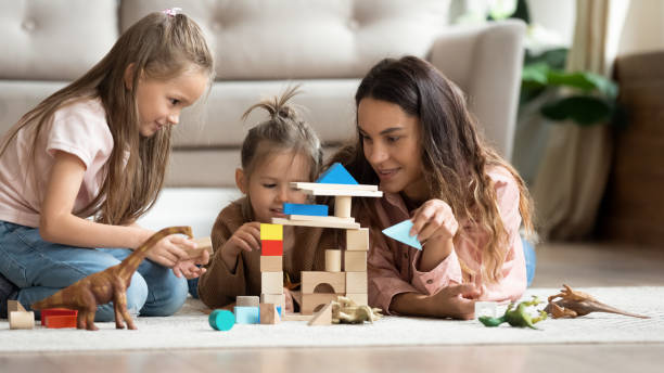 mother play wooden blocks with two little daughters at home - women group of people lying down mother imagens e fotografias de stock