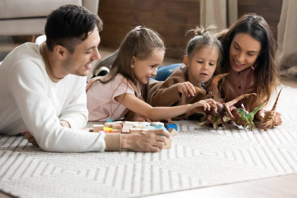 Couple lying on floor play with little daughters
