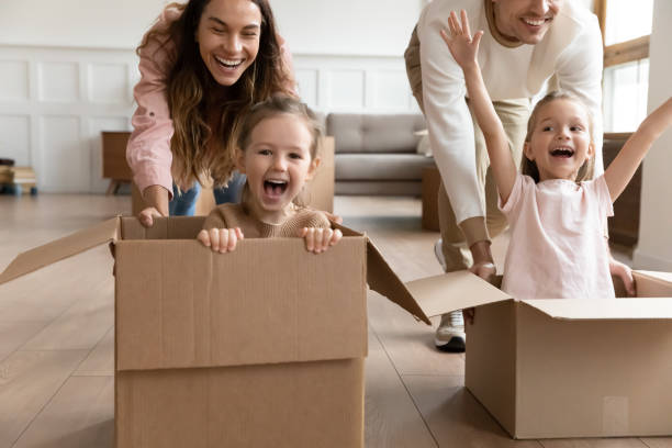istock Parents push daughters sitting inside of boxes compete in races 1309383520