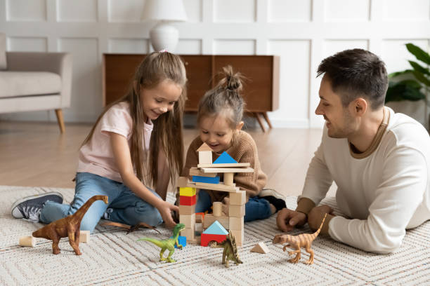 istock Father play with daughters building tower with wooden blocks 1309383530