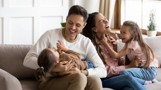 istock Parents play with daughters sit on couch in living room 1309383536