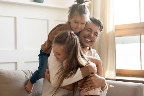 istock Little daughters cuddling loving dad congratulate him Happy Father Day 1309383601