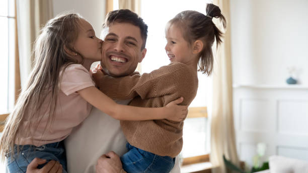 istock Happy father holding hugging two pretty daughters 1309383618