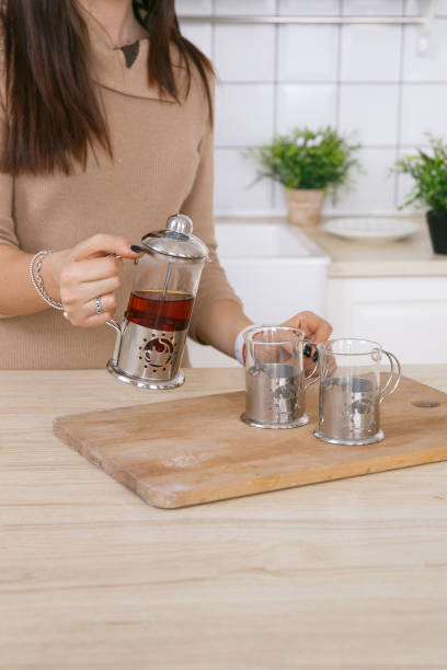 istock A woman in a light scandinavian kitchen pours tea from a teapot into a mug 1309384491