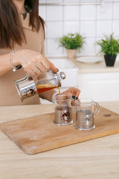 istock A woman in a light scandinavian kitchen pours tea from a teapot into a mug 1309384498