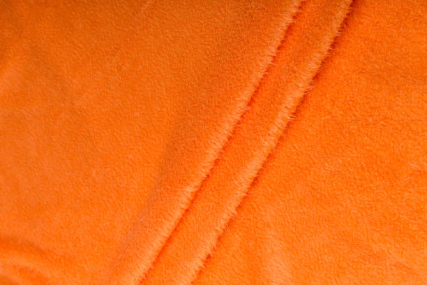 istock Colored orange textile satin fabric folded in folds and waves with highlights and texture 1309384523