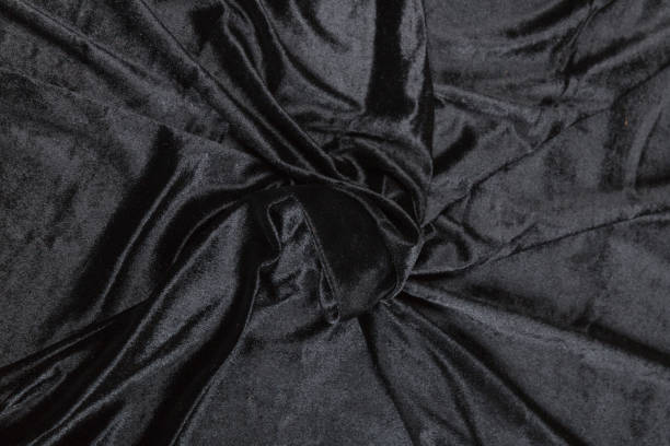 istock Colored black textile satin fabric folded in folds and waves with highlights and texture 1309384591