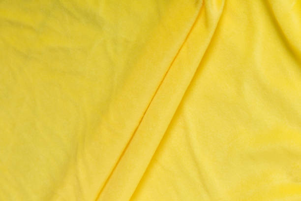istock Colored yellow textile satin fabric folded in folds and waves with highlights and texture 1309384748