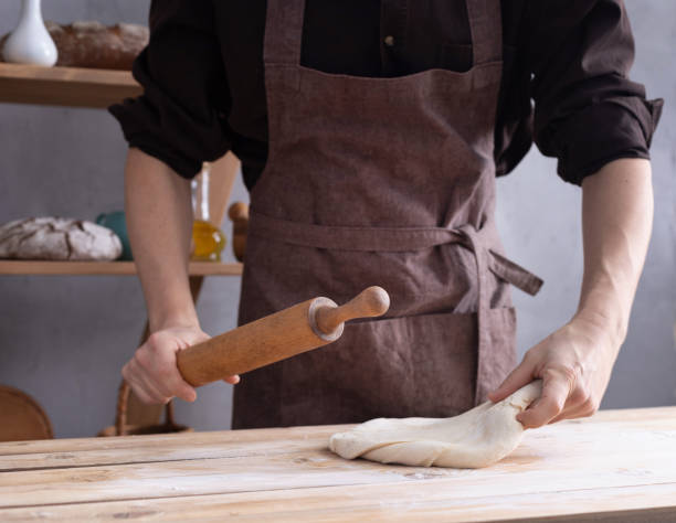 istock Baker man kneading or making dough and bakery ingredients for homemade bread cooking on shelf. Bakery concept 1309386253
