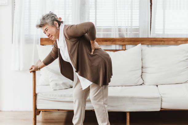 asiatische seniorin schmerzen von rückenschmerzen allein zu hause - osteoporose stock-fotos und bilder