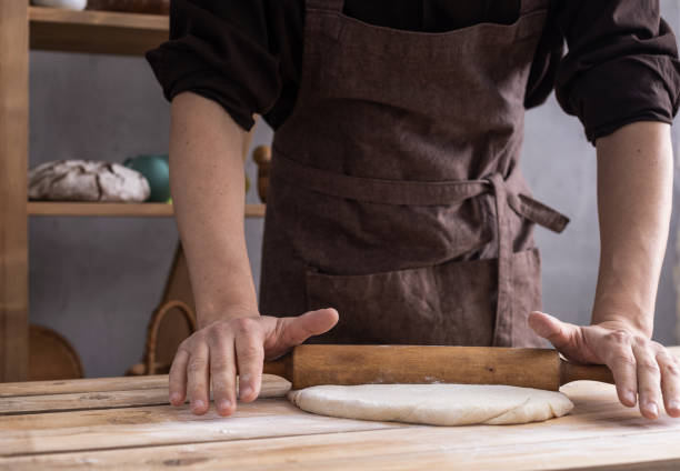 istock Baker man kneading or making dough and bakery ingredients for homemade bread cooking on shelf. Bakery concept 1309386304