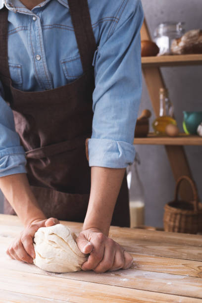 istock Baker man kneading or making dough and bakery ingredients for homemade bread cooking on shelf. Bakery concept 1309386335