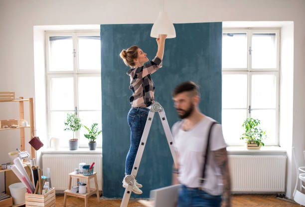 istock Mid adults couple changing light bulb indoors at home, relocation and diy concept. 1309387130