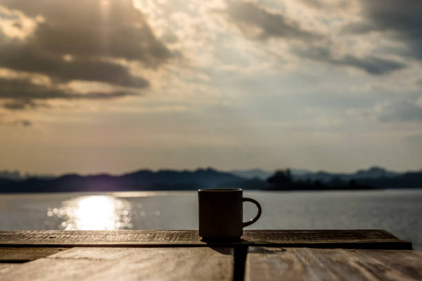 istock Silhouette coffee mug on wooden with blur background 1309387173