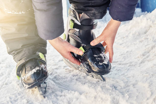 istock Boy in jacket and pants adjusts ice skates standing on snow 1309389324