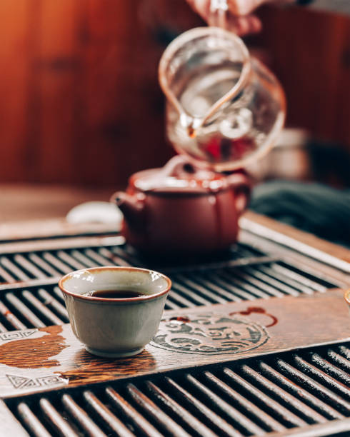 istock Chinese tea ceremony, a man pours tea into cups on a bamboo table, sunlight 1309390124