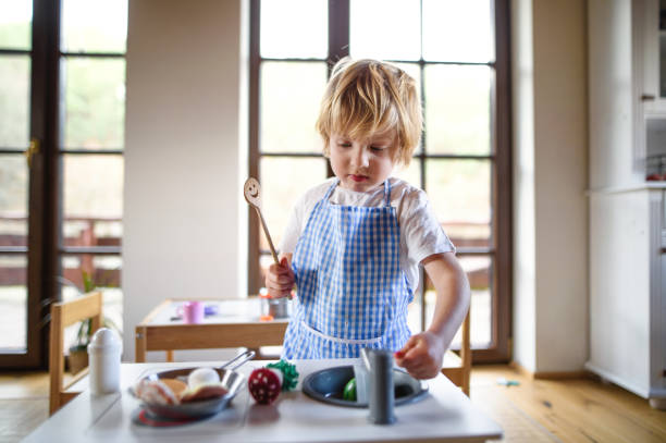 istock Small boy with apron playing indoors with toy kitchen at home. 1309390165