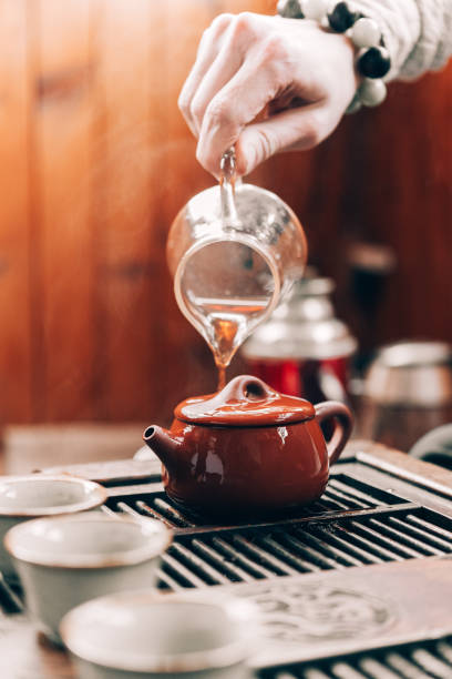 istock Chinese tea ceremony, a man pours tea into cups on a bamboo table, sunlight 1309390523