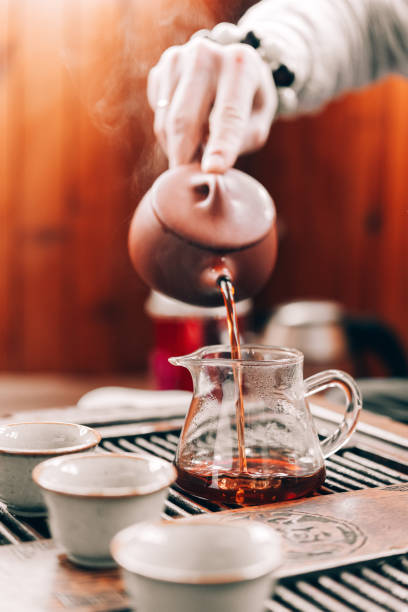 istock Chinese tea ceremony, a man pours tea into cups on a bamboo table, sunlight 1309393364