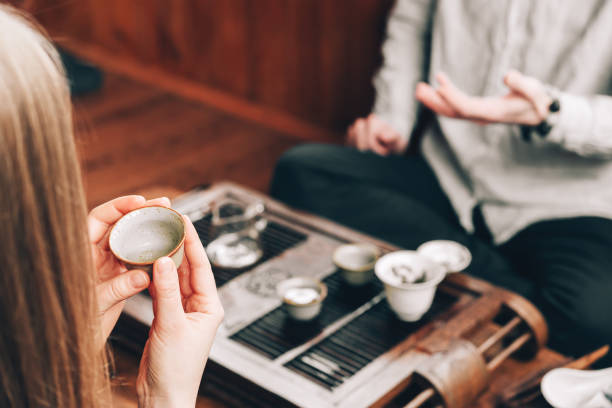 istock Tea ceremony.Chinese Tea Tasting.Girl drinks tea from a ceramic bowl, people communicate in a cafe setting 1309394328