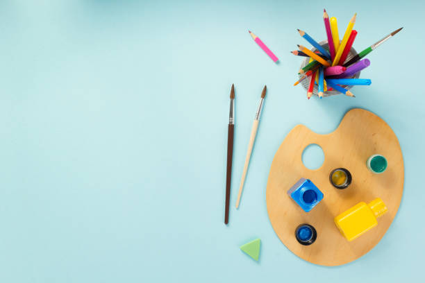 istock Palette and paint brush on abstract paper background. Painter tools on table and paintbrush 1309394790