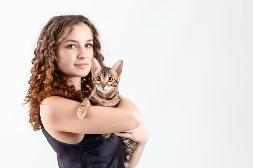 Young beautiful woman with bengal cat isolated on white background. Copy space