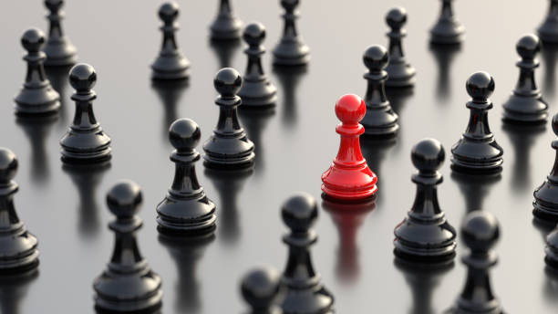 Leadership concept, red pawn of chess, standing out from the crowd of black pawns, on white background stock photo