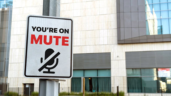You're on mute sign in a downtown city setting