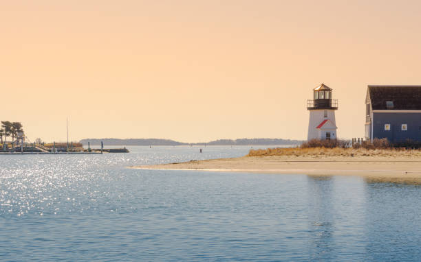 Seascape with Lewis Bay Lighthouse in Hyannis Harbor. Historic Light House across from Hyannis Harbor Park at Hyannis Inner Harbor. Sunrise over the iconic Cape Cod lighthouse in Hyannis Harbor at the waterway of Lewis Bay. Soft morning sunray spreading over the tranquil seashore. cape cod photos stock pictures, royalty-free photos & images