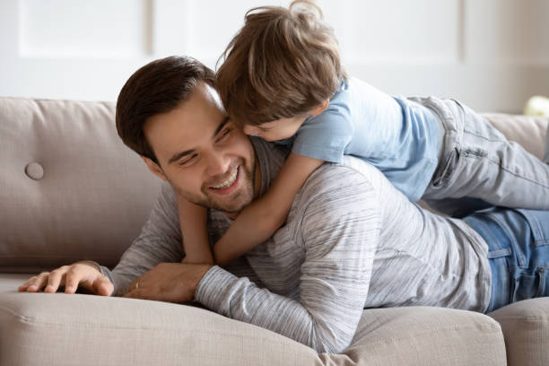 istock Close up happy father and son hugging, lying on couch 1309403942