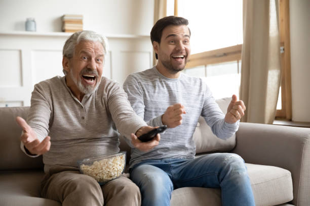 istock Overjoyed mature father with son watching tv, having fun together 1309403984