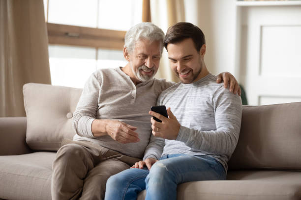 istock Happy older father and son using phone at home together 1309404505
