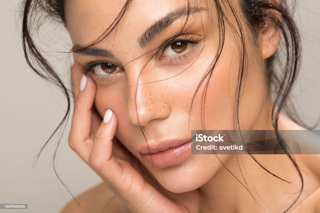 Beauty portrait of young brunette Close up studio shot of a beautiful brunette woman with glowing skin. Holding hands near her face. Beauty Stock Photo
