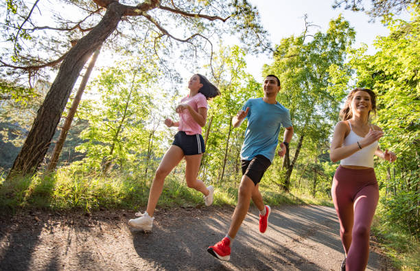 trois personnes exécutant dans le stationnement public au coucher du soleil. - nordic running photos et images de collection